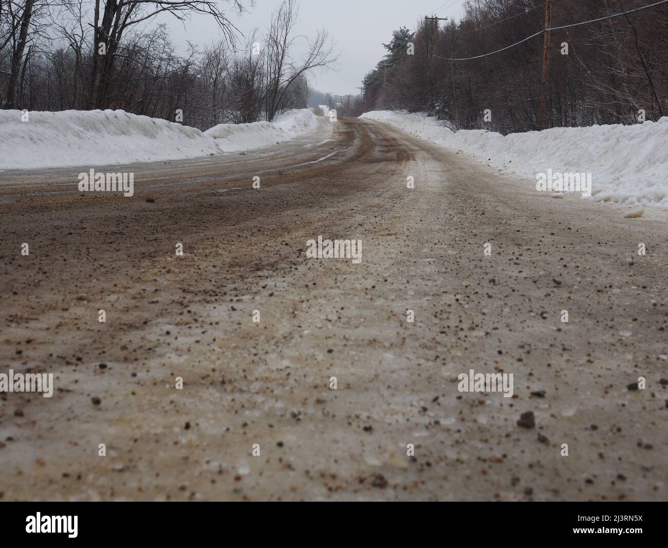 Sand breitete sich im Winter auf einer vereisten Straße aus, um Traktion zu erhalten. Quebec, Kanada Stockfoto