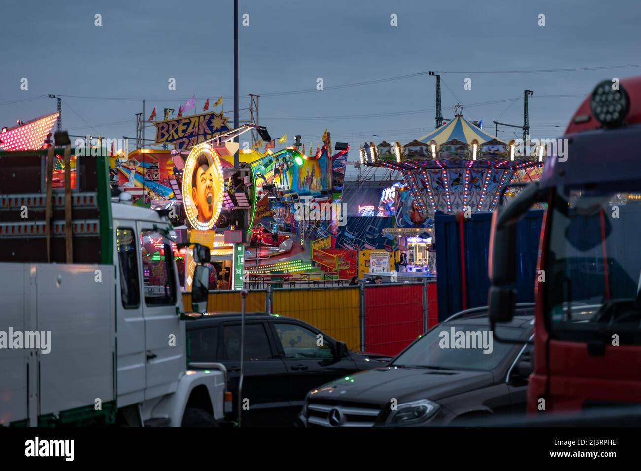 Funfair Fahrten auf dem Messegelände in der Stadt. Beleuchtete Attraktionen für Freizeitaktivitäten. Blick vom Parkplatz auf das Festivalgelände. Stockfoto