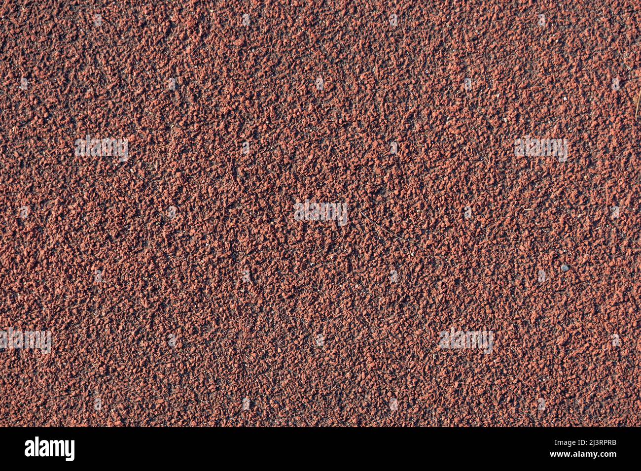 Gummi Laufspur Textur Hintergrund. Oberfläche eines roten Polyurethan-Tartan-Sportgrunds. Kleine Steine und Schmutz sind in den Lücken. Spielplatz Stockfoto