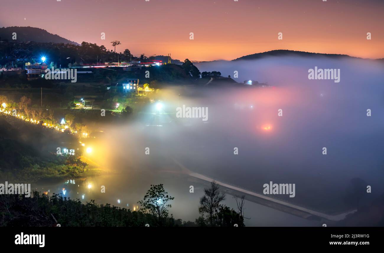 Nachtszene am Hang eine kleine Stadt im Nebel, umgeben von bunten Häusern und Lichtern, macht die Nacht im Hochland von Da Lat, Vietnam, so schön Stockfoto