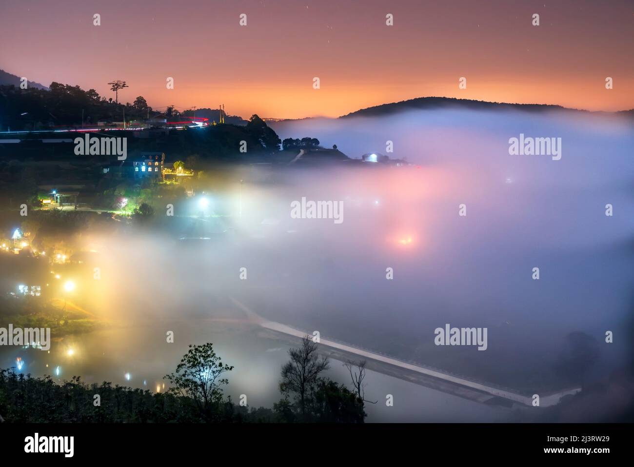 Nachtszene am Hang eine kleine Stadt im Nebel, umgeben von bunten Häusern und Lichtern, macht die Nacht im Hochland von Da Lat, Vietnam, so schön Stockfoto