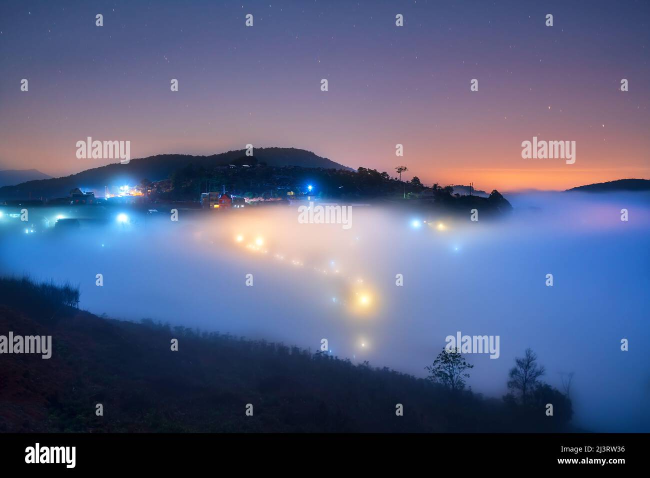 Nachtszene am Hang eine kleine Stadt im Nebel, umgeben von bunten Häusern und Lichtern, macht die Nacht im Hochland von Da Lat, Vietnam, so schön Stockfoto