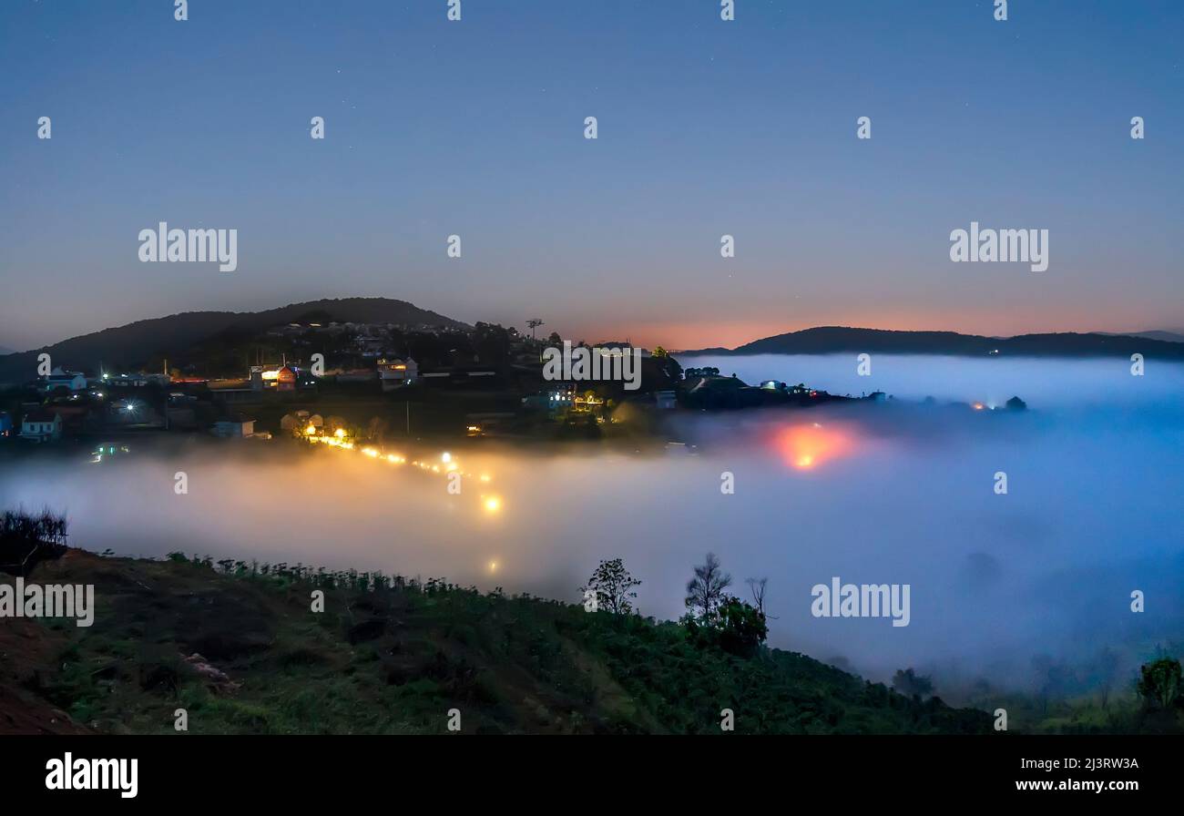Nachtszene am Hang eine kleine Stadt im Nebel, umgeben von bunten Häusern und Lichtern, macht die Nacht im Hochland von Da Lat, Vietnam, so schön Stockfoto