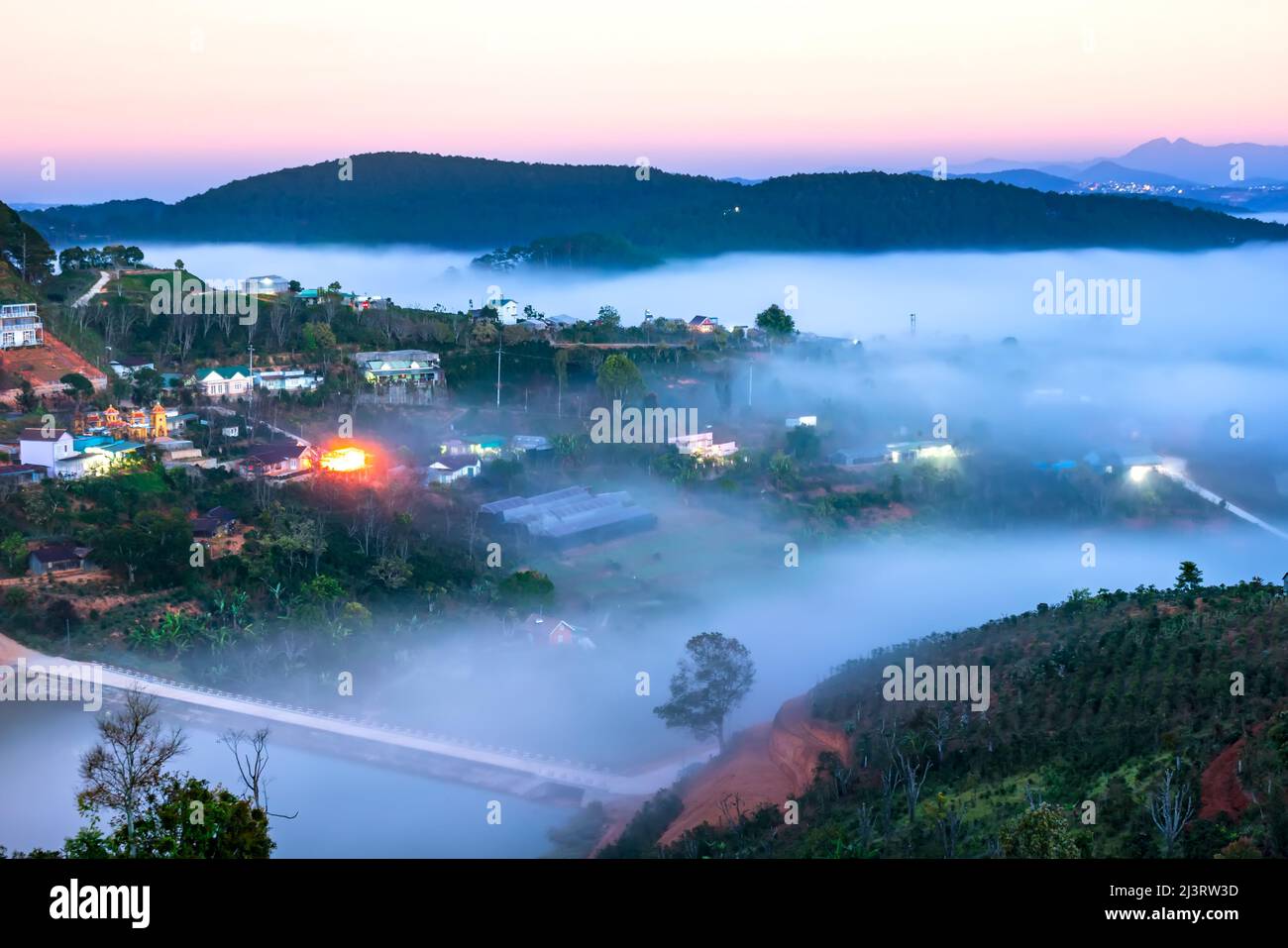 Nachtszene am Hang eine kleine Stadt im Nebel, umgeben von bunten Häusern und Lichtern, macht die Nacht im Hochland von Da Lat, Vietnam, so schön Stockfoto