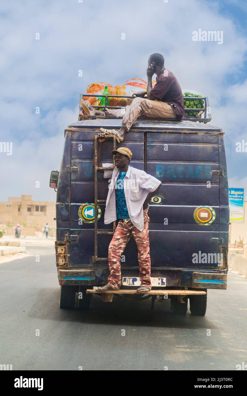 Senegal. Junge Männer fahren auf der Oberseite oder dem Heck von zwischenstädtischen Personenwagen oder Bussen. Stockfoto