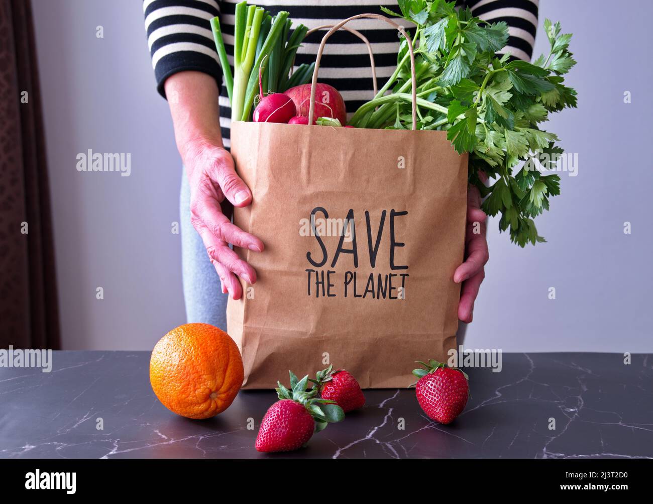 Mittelteil einer älteren Frau, die nach dem Einkaufen einen Papierbeutel mit Obst und Gemüse in der Hand hält Stockfoto