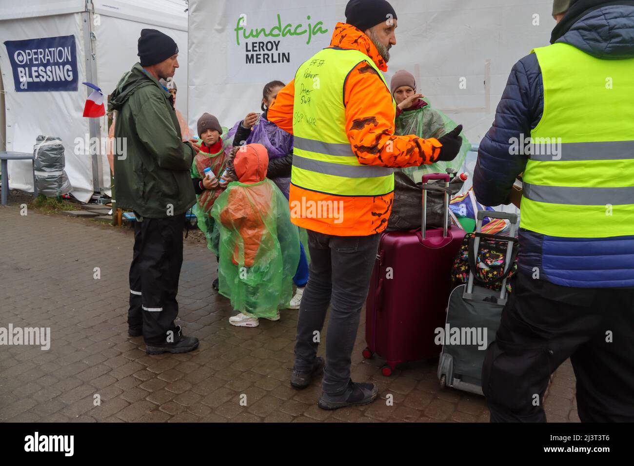 Medyka, Polen. 8. April 2022. Ukrainer Flüchtlinge, die vor Putins Terror fliehen, kommen gestresst, müde und kalt im eisigen Regen im Medyka Border Camp in Polen an. Regenponchos und Mittagessen, die von der internationalen Gemeinschaft gespendet und von engagierten Freiwilligen verteilt werden, deren Spirituosen nicht gedämpft werden können, erleichtern ihre Probleme etwas. (Bild: © Amy Katz/ZUMA Press Wire) Stockfoto