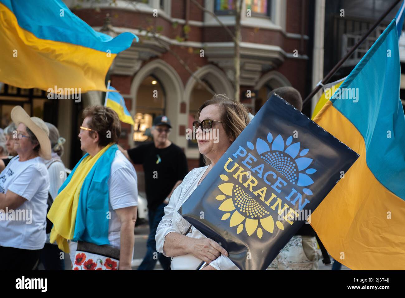 Melbourne, Australien. 10. April 2022. Eine Frau, die ein Schild mit der Aufschrift „Frieden in der Ukraine“ hält, marschiert mit einer Anti-Kriegs-Kundgebung in Melbourne zur Unterstützung der Ukraine. Quelle: Jay Kogler/Alamy Live News Stockfoto