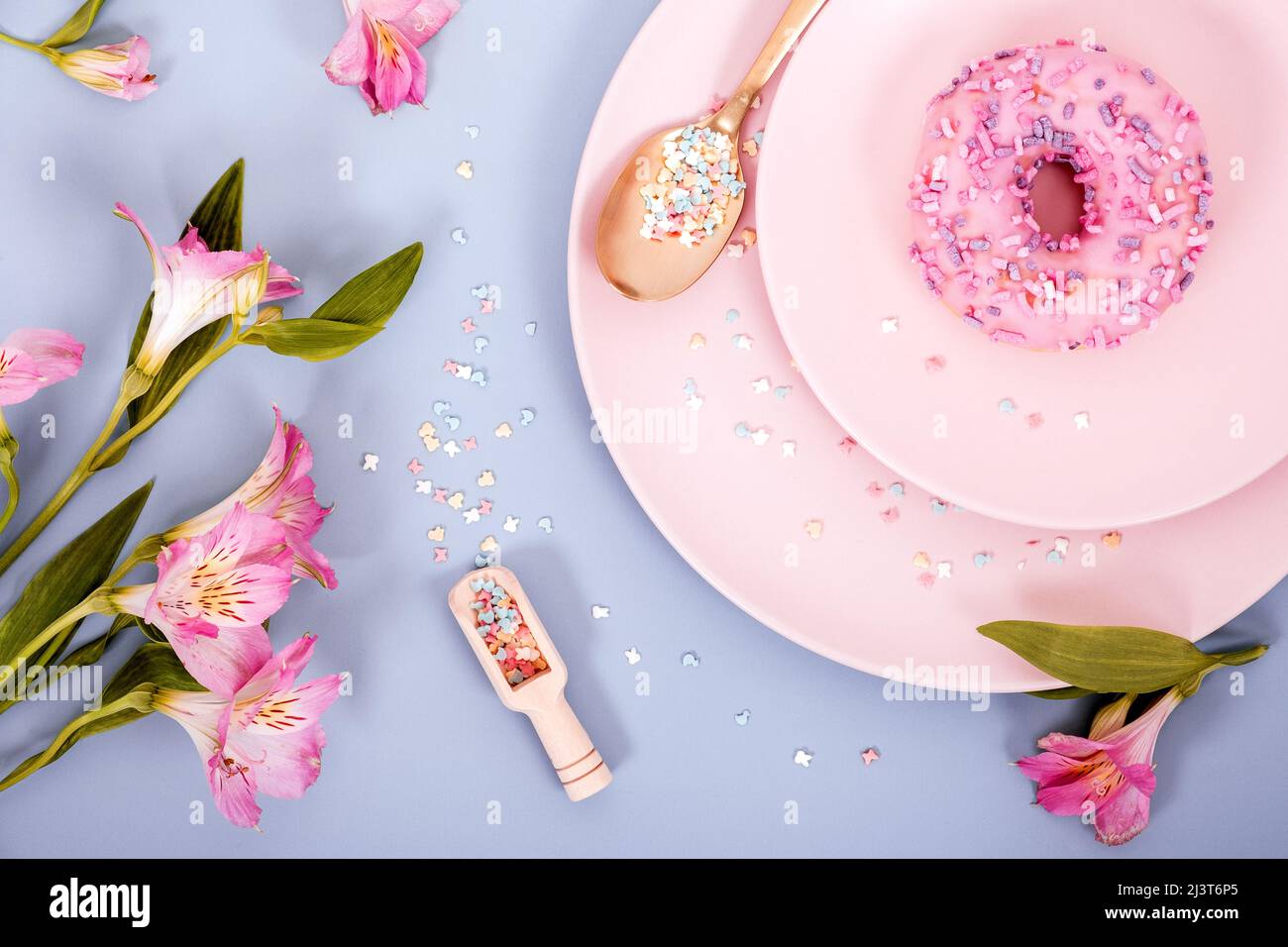 Draufsicht flach Lay Frühling oder Sommer Komposition in pastellrosa und blauen Farben von Tellern, Donut und Blumen. Selektiver Fokus. Stockfoto