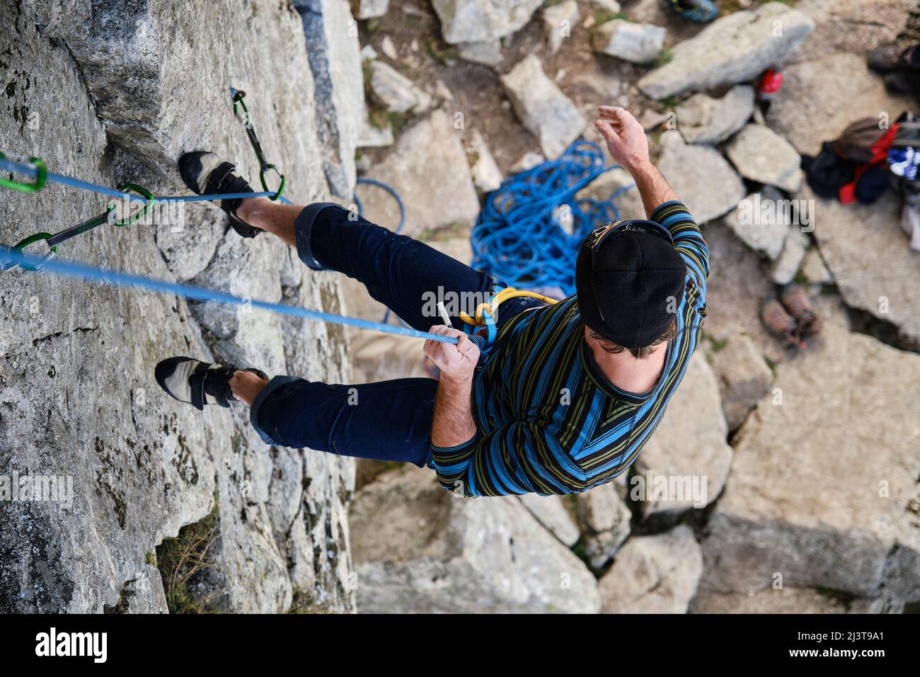 Ein reifer Kletterer, der das Seil auf die Felswand herabsteigt. Stockfoto