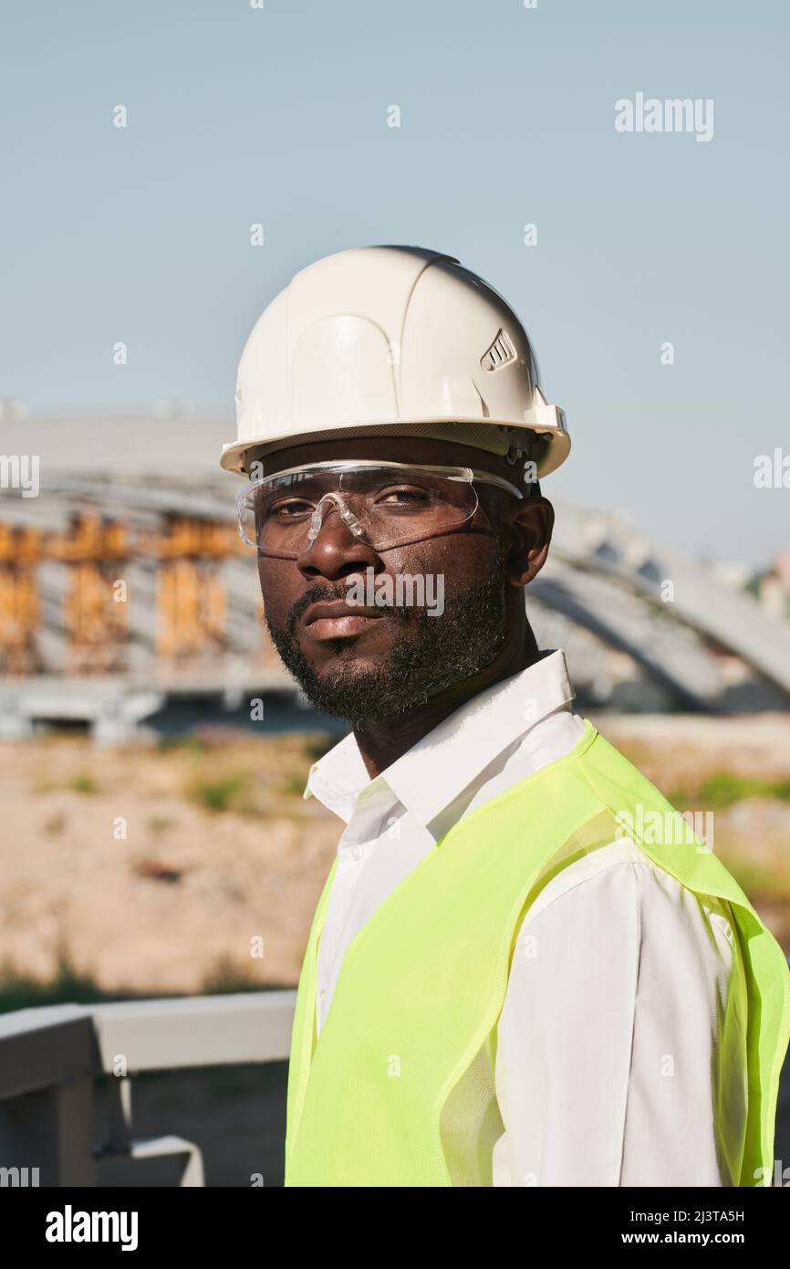 Porträt eines jungen männlichen Ingenieurs, der auf der Baustelle posiert Stockfoto