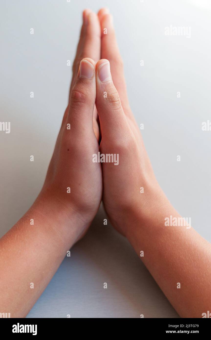 Betende Hände auf einem hellgrauen Hintergrund, Konzept des Glaubens und des Glaubens. Stockfoto