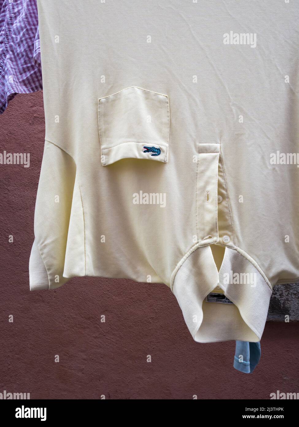 Nasses Lacoste Poloshirt, das draußen auf der Wäscheleine trocknet Stockfoto