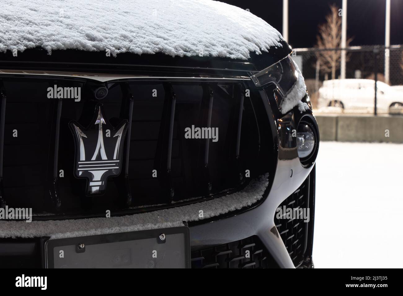 Das Emblem-Logo von Maserati, einem italienischen Hersteller von Luxusfahrzeugen, ist auf dem Kühlergrill eines neuen Autos zu sehen, das bei einem Autohaus geparkt ist. Stockfoto