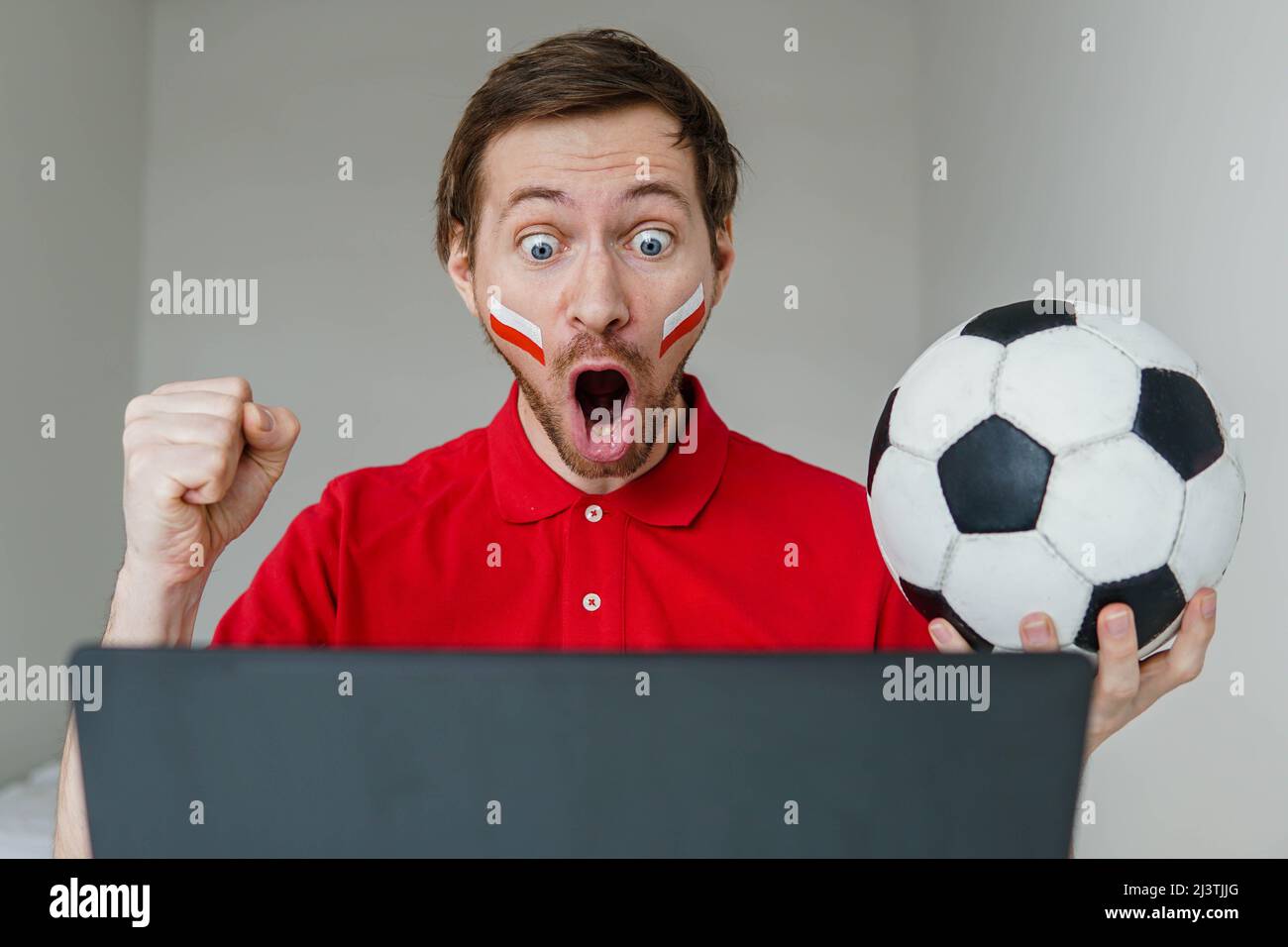 Junge aufgeregt Mann Fan unterstützen Polen Fußballnationalmannschaft halten in der Hand Fußball Fernsehen Live-Stream auf Laptop. Stockfoto