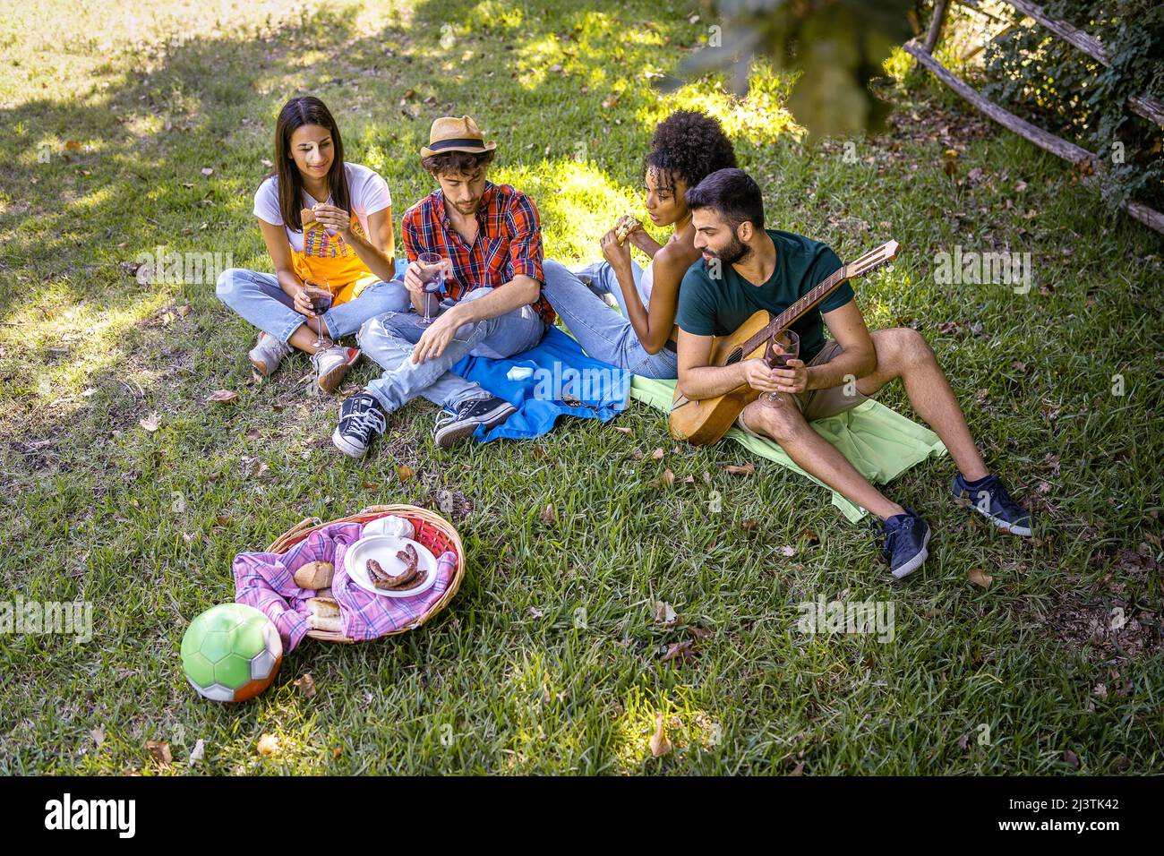 Eine Gruppe junger, glücklicher Freunde, die sich mit einem Picknick im Freien treffen - Menschen, die Spaß haben und beim Grillen auf einer Grillparty auf dem Land feiern Stockfoto