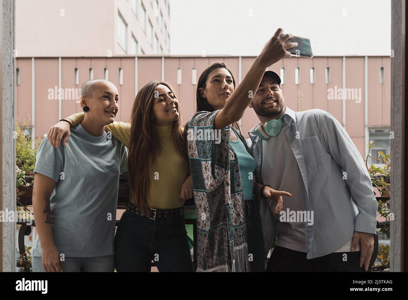 Fröhliche, vielfältige Menschen, die auf dem Balkon eines Hostelzimmers Selfie machen Stockfoto