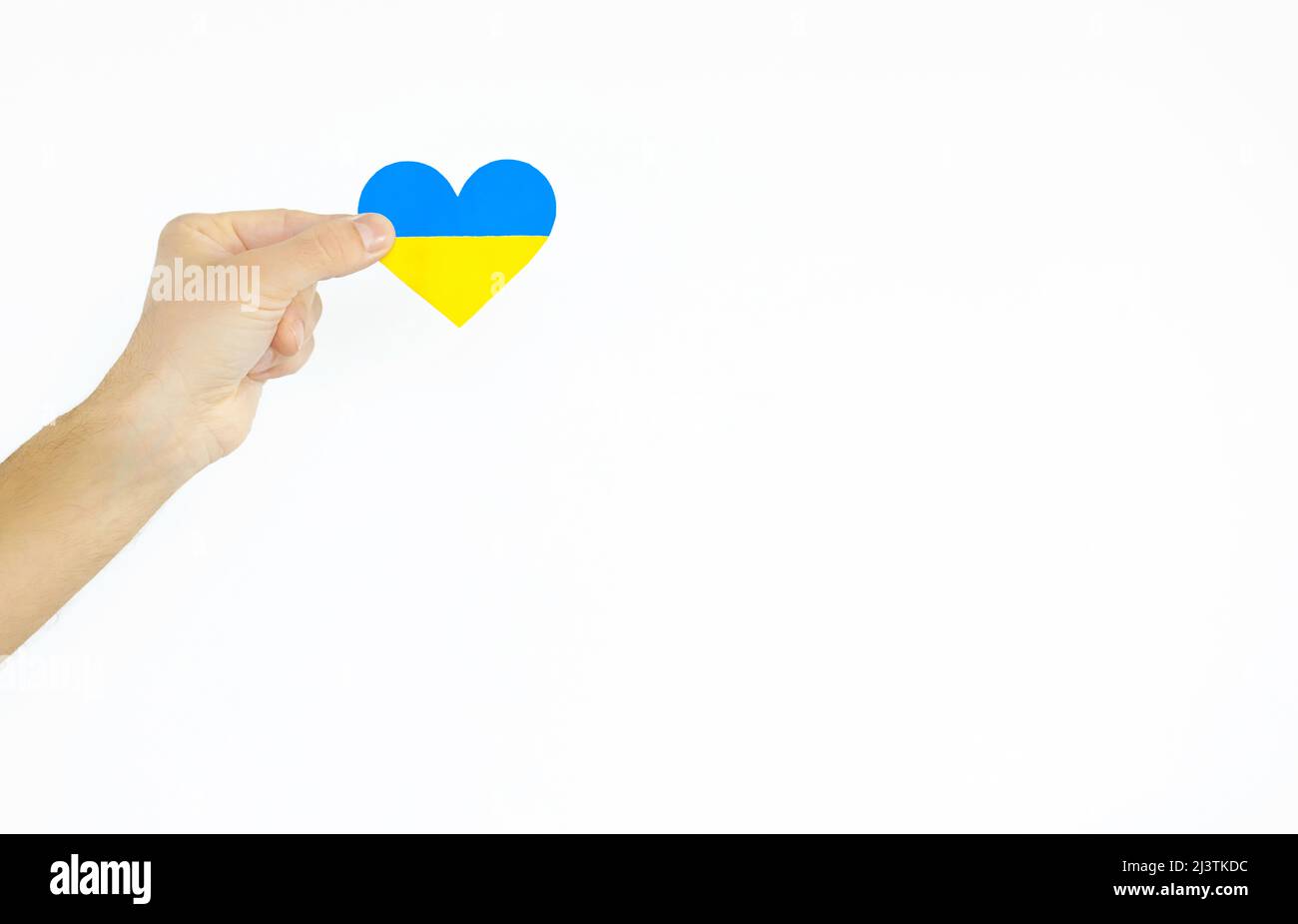 Das Konzept der Liebe zur Ukraine. Herz in den Farben der Flagge der Ukraine in Männerhand auf weißem Hintergrund. Stockfoto