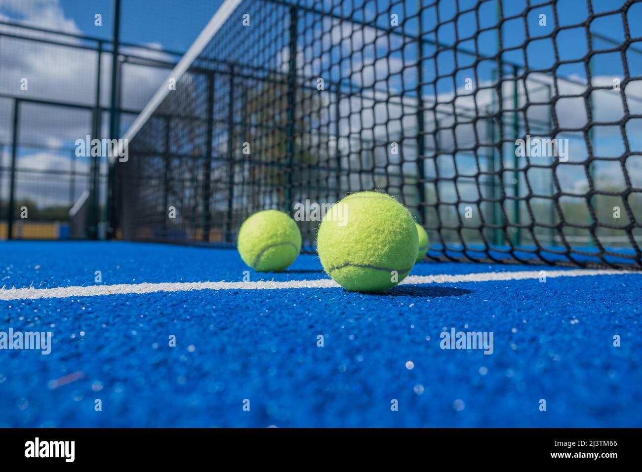 Kugeln neben dem Netz und der Mittellinie eines blauen Paddle-Tennisplatzes für Schlägersportkonzepte Stockfoto