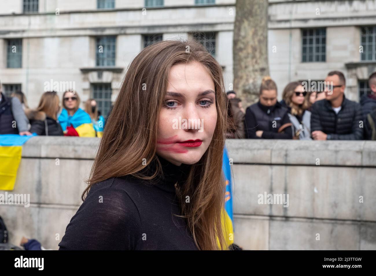 London, Großbritannien. 9. April 2022. Hunderte von Ukrainern simulieren ihren Tod bei einem Todesfall mit gefesselten Händen hinter ihrem Rücken und Frauen malen Blut auf ihre Gesichter, um gegen die andauernde russische Invasion der Ukraine gegenüber der Downing Street zu protestieren. Stockfoto