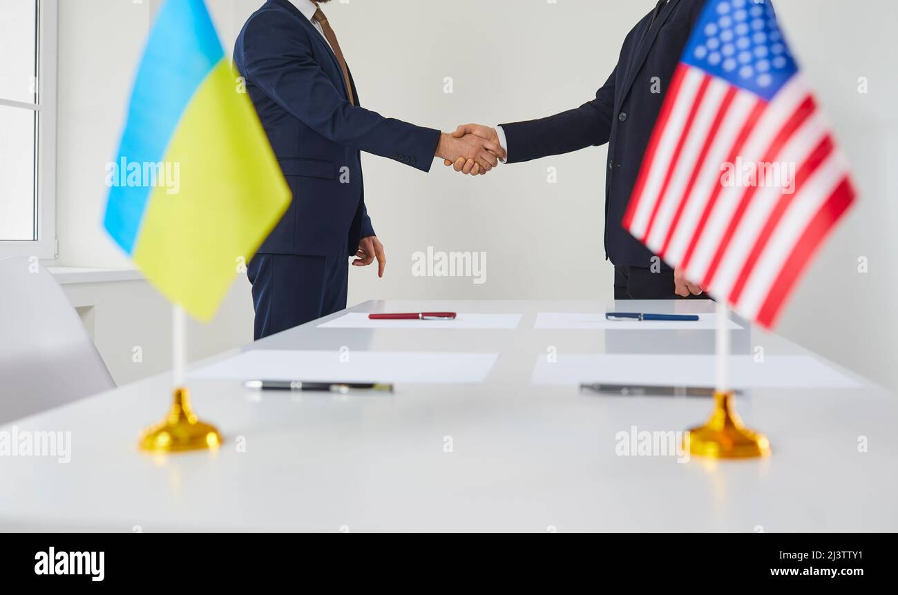 Diplomaten des ukrainischen Staates und der Vereinigten Staaten von Amerika schütteln als Zeichen der Einigung die Hände. Stockfoto