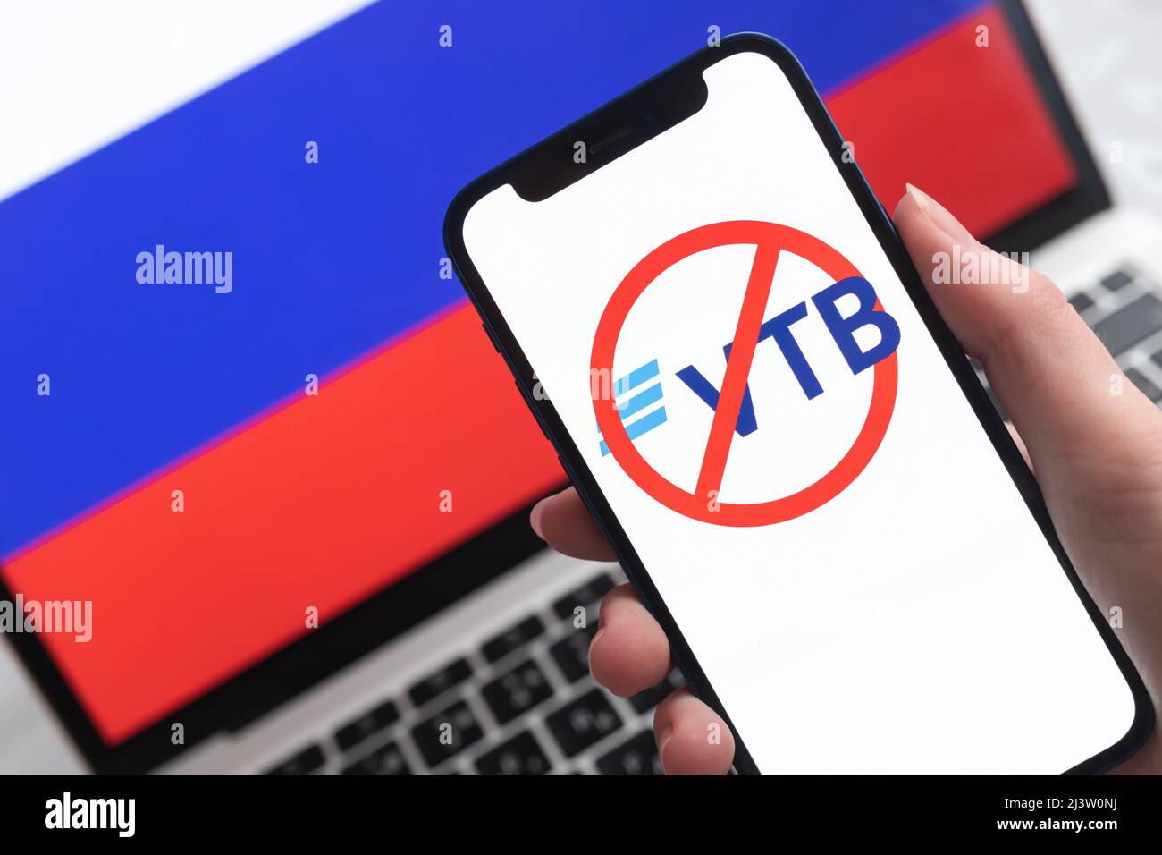 SPB, Russland - 8. April 2022: VTB-Bank und Sanktionen. Blockierte russische Bank, Logo und Ban-Symbol auf Handy-Bildschirm und Flagge Hintergrund Stockfoto