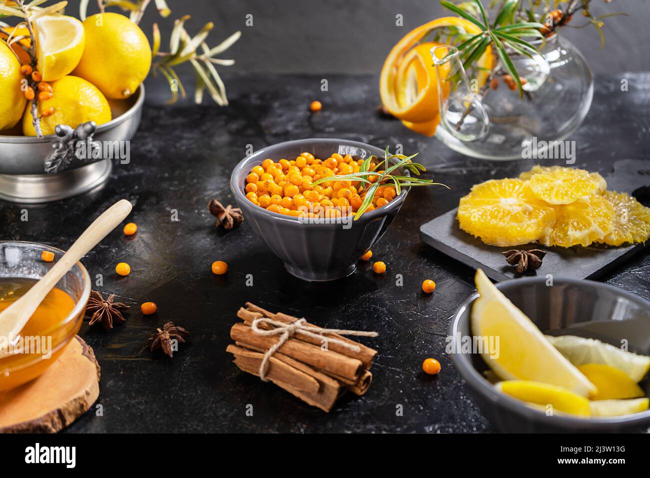 Gesunde Sanddorntee-Zutaten: Beeren, Orange, Zitrone, Zimt, Anissterne und Honig Stockfoto