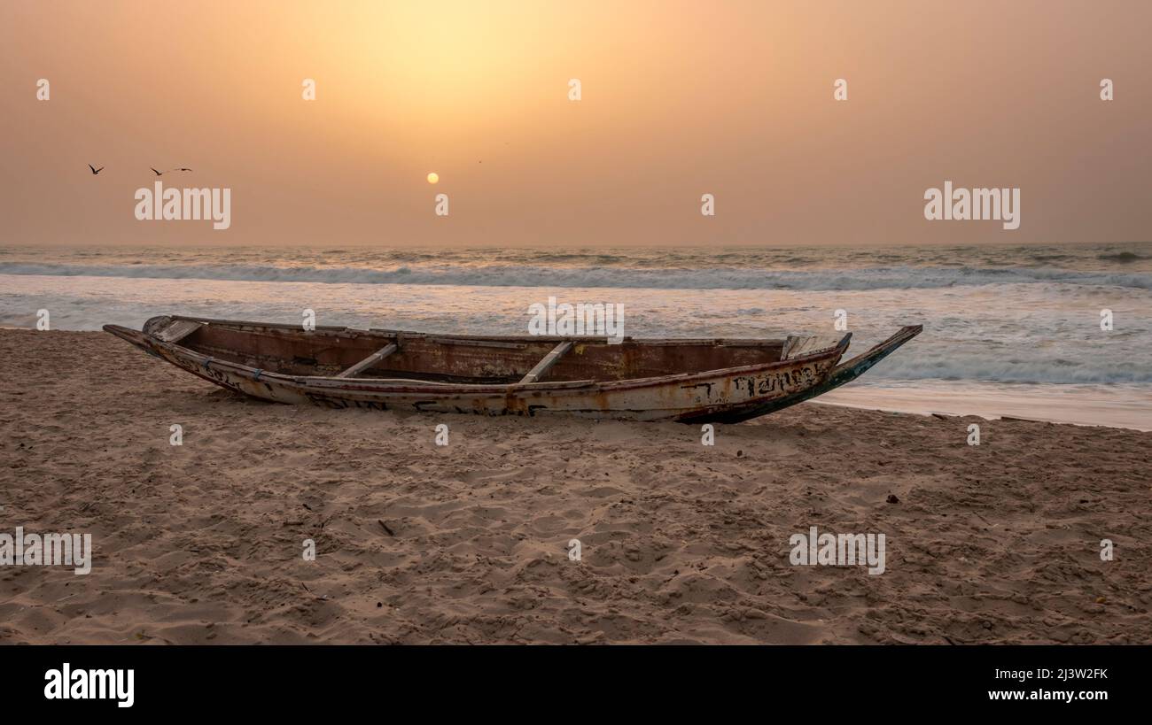 Verlassen Sie das verlassene Fischerboot am Strand von Bijilo während des Sonnenuntergangs an der westafrikanischen Küste von Gambia Stockfoto