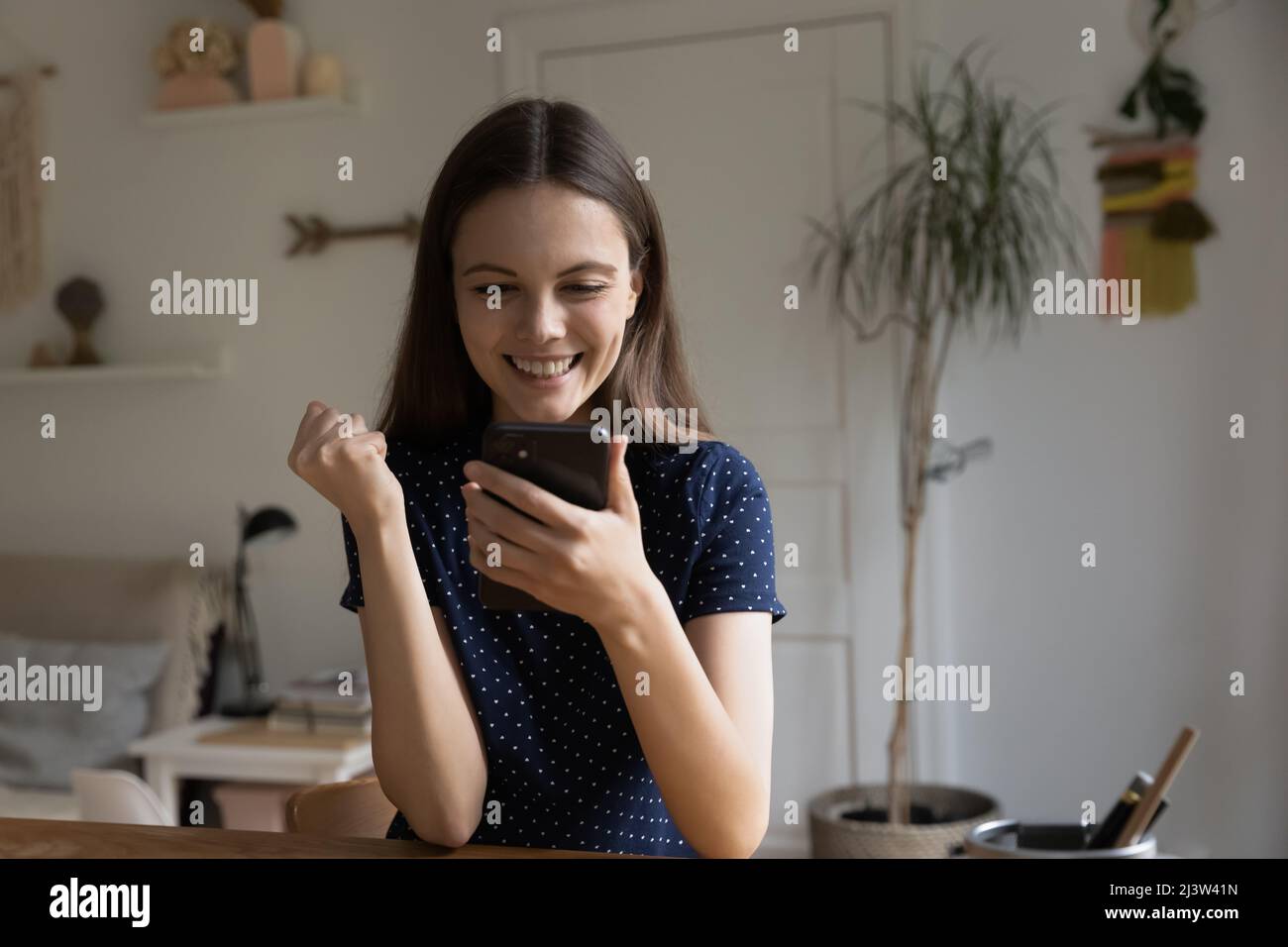 Frau, die auf den Handybildschirm starrt, fühlt sich glücklich über gute Nachrichten Stockfoto