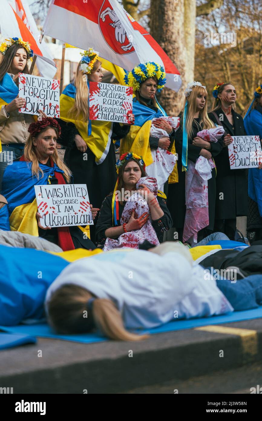 Eine Gruppe von pro-ukrainischen osteuropäischen Frauen demonstriert gegen den Krieg mit Russland, während andere auf dem Boden liegen. Ukrainische Flaggen und gelbe Blume Stockfoto