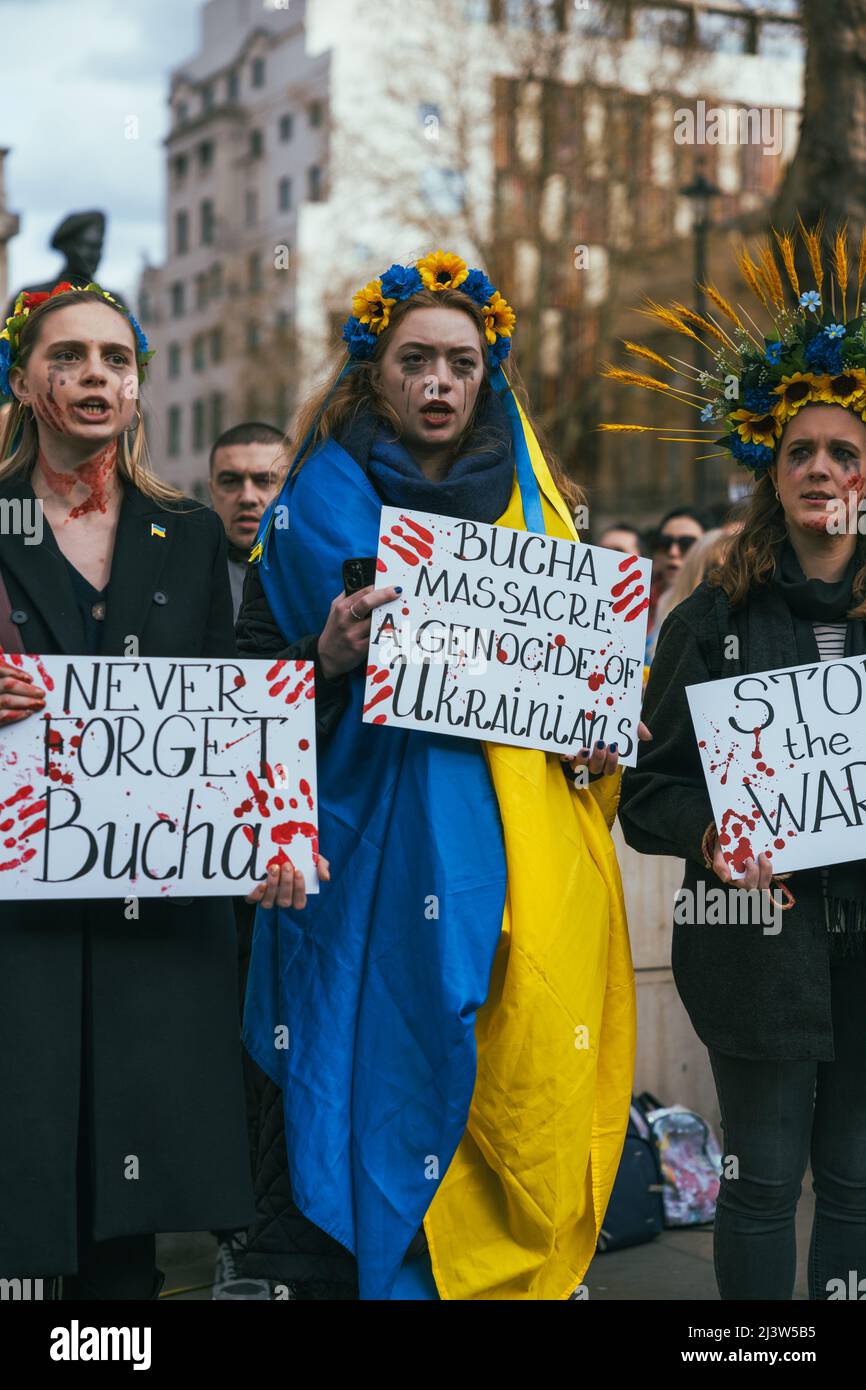 Osteuropäische Frauen demonstrieren gegen die russische Invasion in der Ukraine. Sie protestieren gegen den Völkermord in Bucha. Ukrainische Flaggen. Weinendes Blut Stockfoto