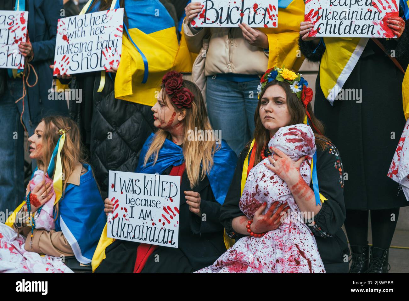 Gruppe pro-ukrainischer Frauen, die gegen den Krieg mit Russland demonstrieren. Gelbes und blaues Blumenband mit ukrainischen Fahnen. Stehe mit der Ukraine. Stockfoto