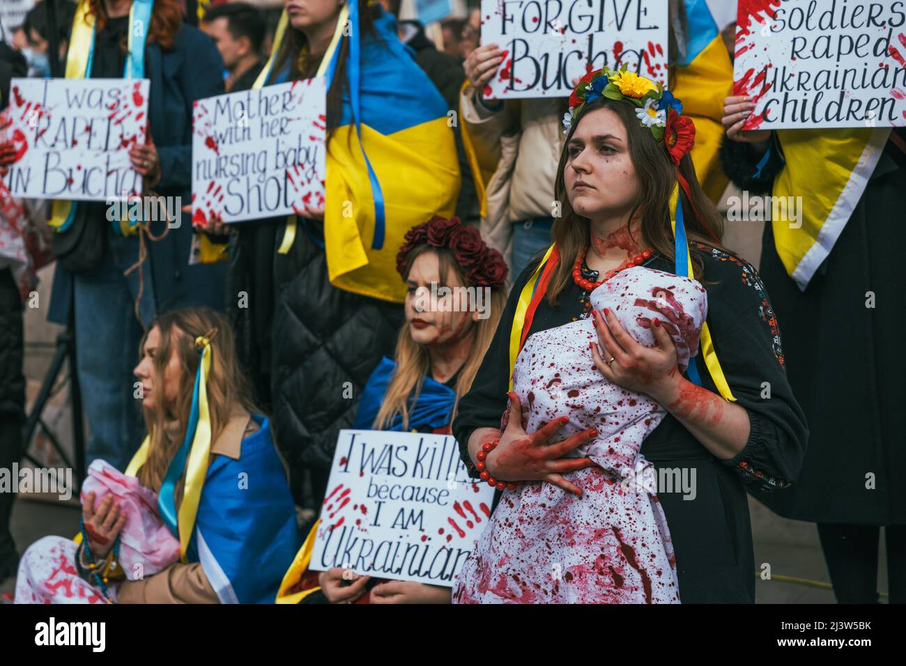 Starke ukrainische Frau protestiert gegen russische Invasion und Völkermord in Bucha. Ukrainische Flaggen gegen den Krieg. Umgeben von Frauen, die für den Frieden kämpfen Stockfoto