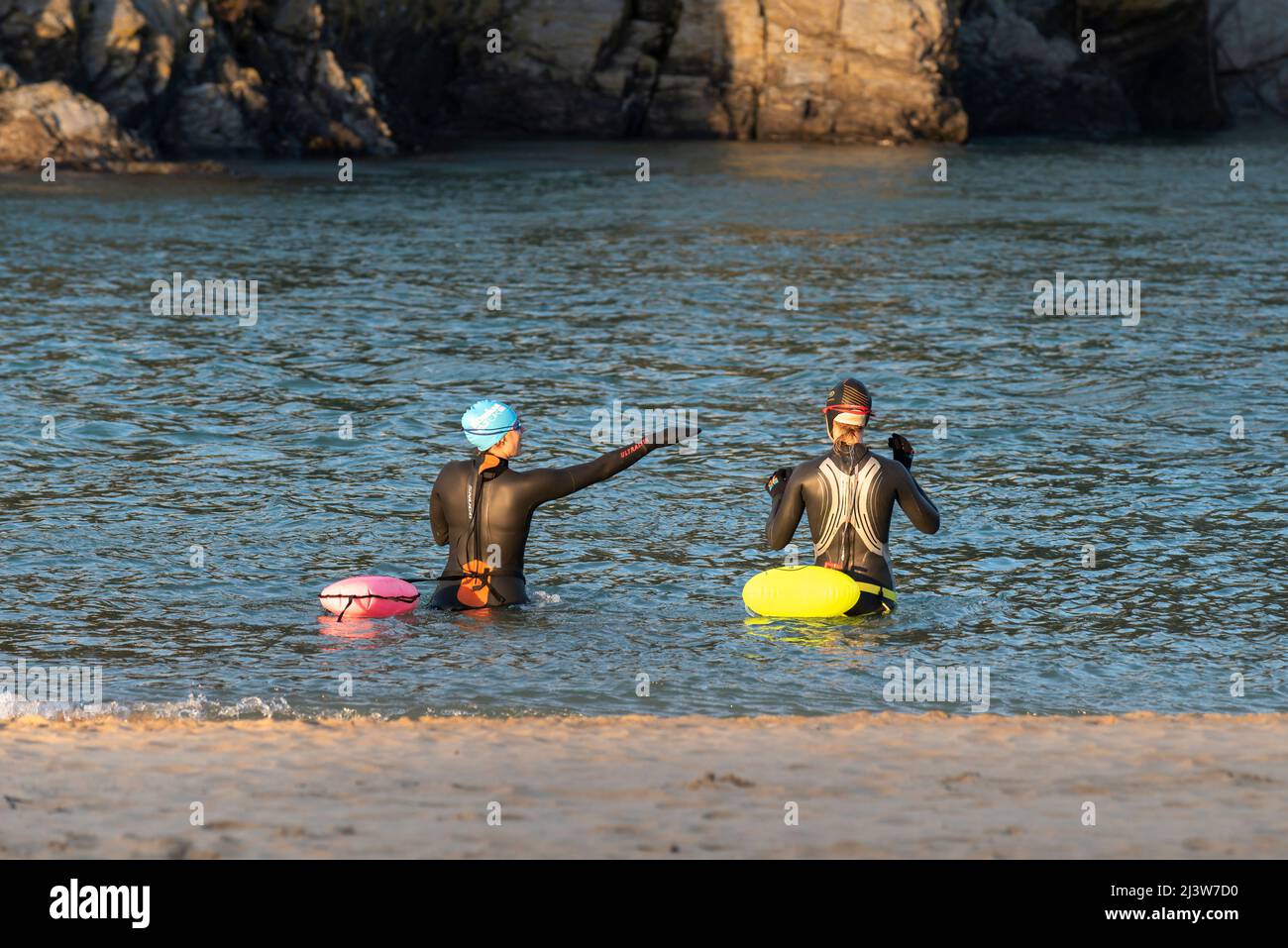 Weibliche Wildschwimmer in Neoprenanzügen mit fluurescent Inflatable Tow schwimmt; im Gannel River am Crantock Beach in Newquay in Cornwall. Stockfoto