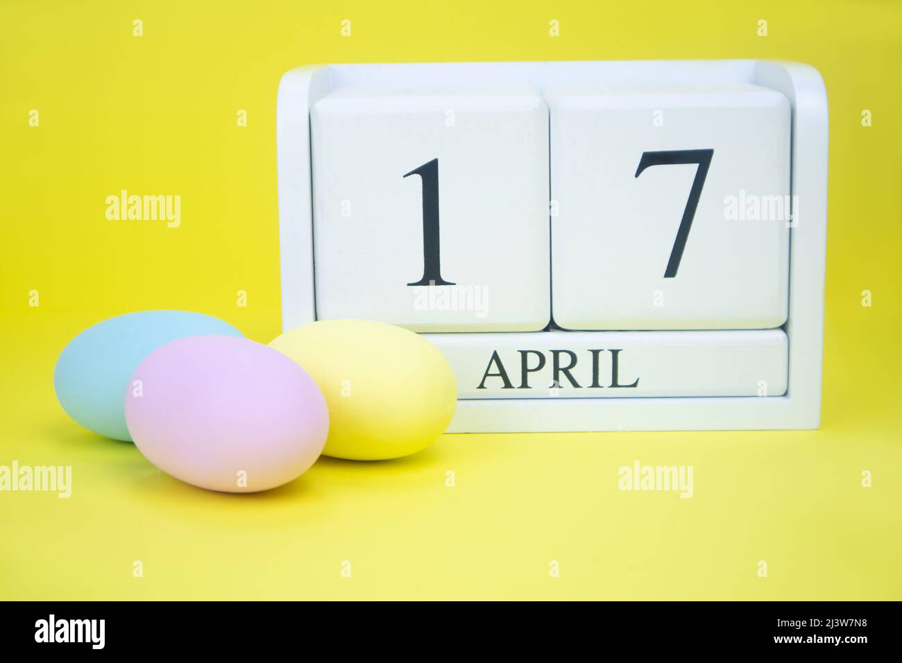 Weißer Holzkalender April 17 und Ostereier auf gelbem Hintergrund Stockfoto