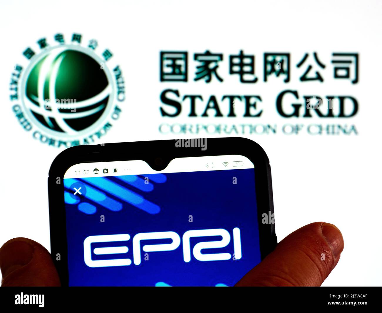 In dieser Abbildung wird das Logo des State Grid Electric Power Research Institute Co., Ltd. Auf einem Smartphone-Bildschirm mit einem Logo der State Grid Corporation of China im Hintergrund angezeigt Stockfoto