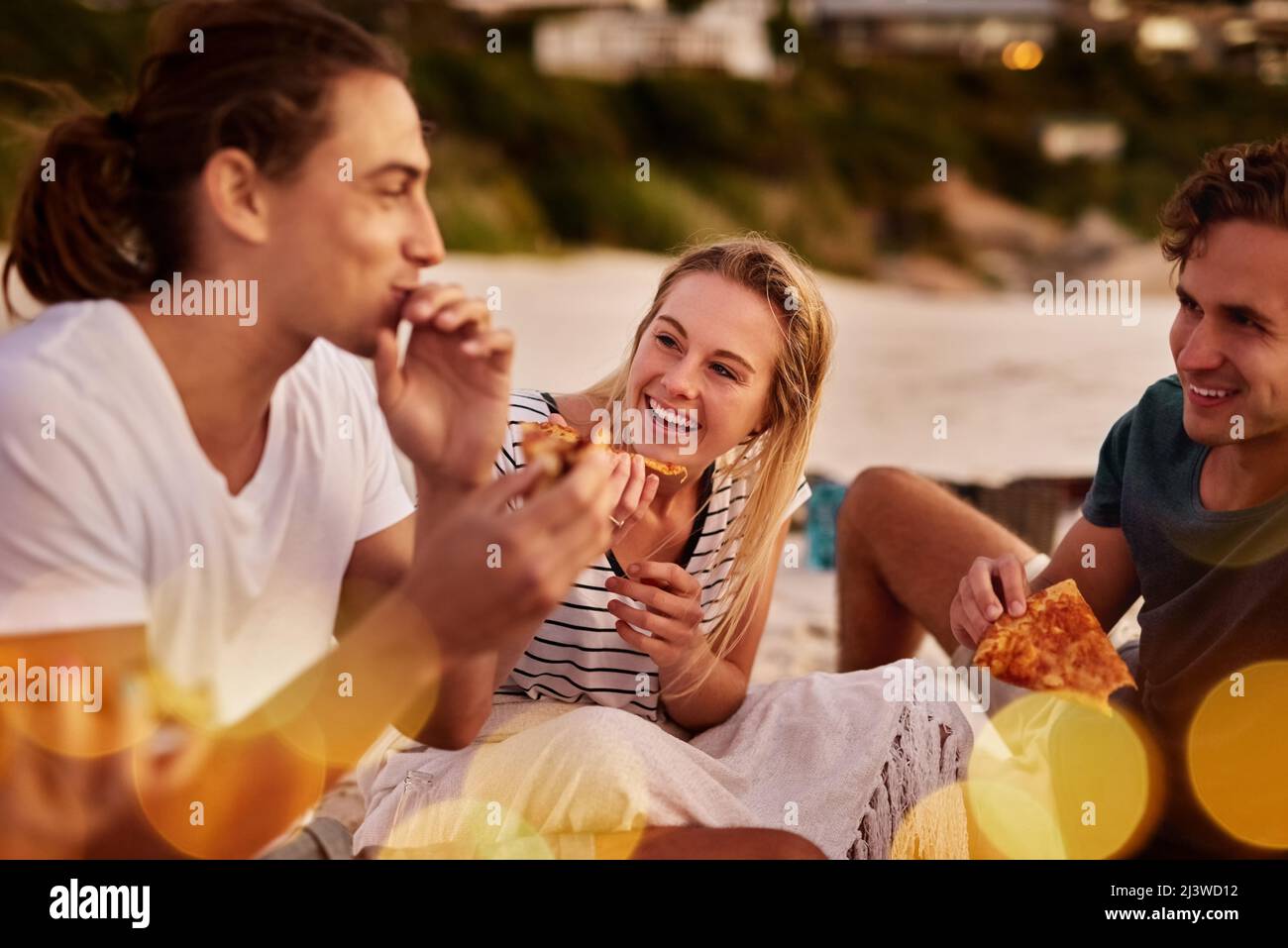 Pizza ist gutes Essen. Aufnahme einer Gruppe von Freunden, die zusammen am Strand sitzen. Stockfoto