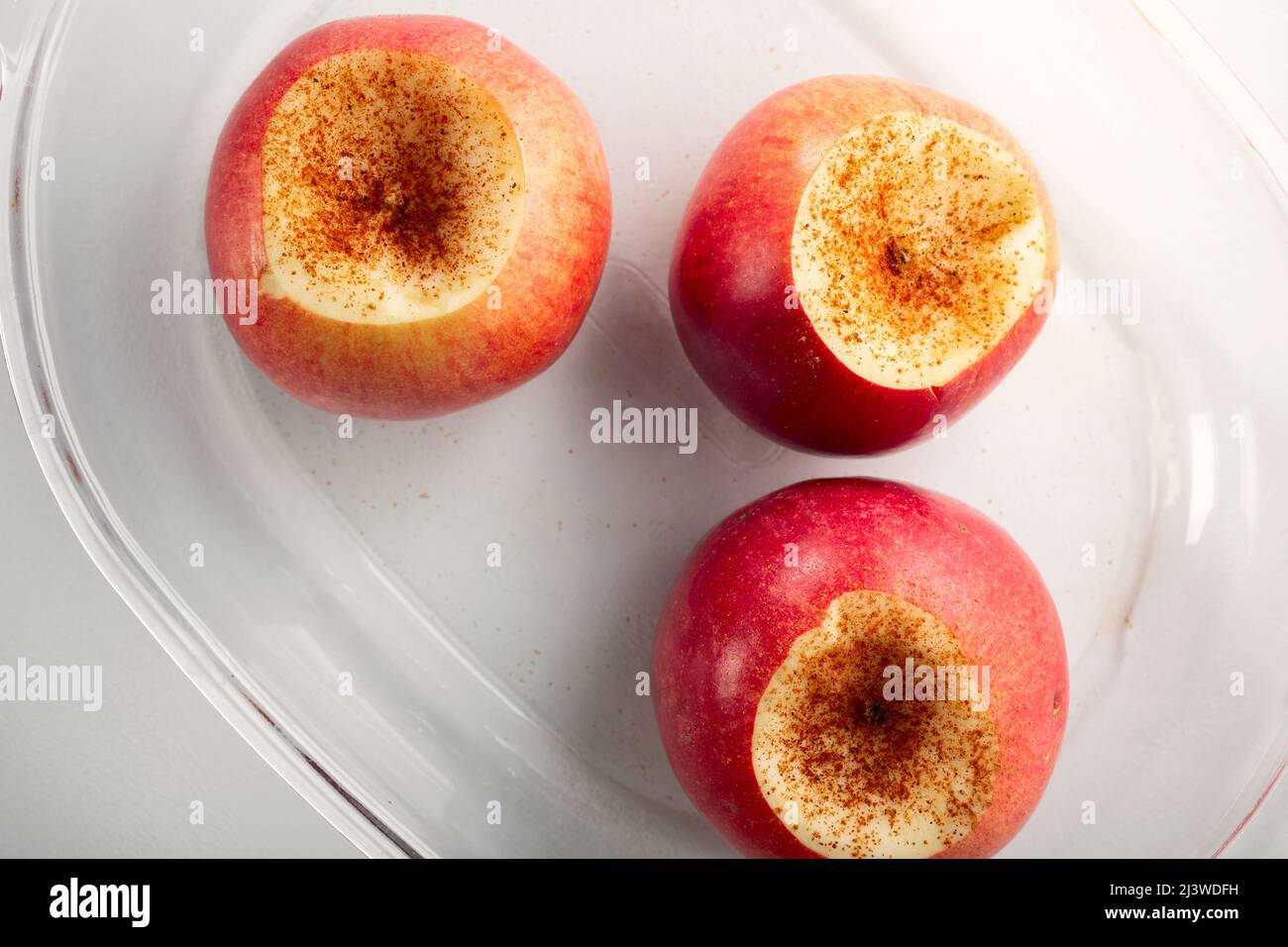 Reife Äpfel werden mit Zimt bestreut und können in den Ofen oder die Mikrowelle geladen werden. Draufsicht. Stockfoto