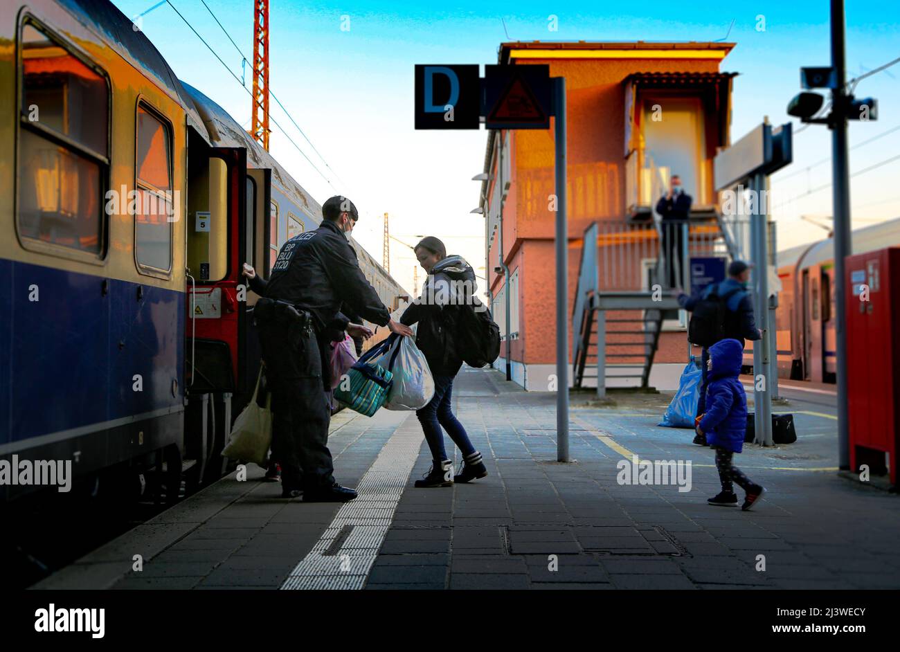 Ein deutscher Grenzpolizist hilft einer ukrainischen Familie, die vor dem Krieg flüchtete, in den Zug zu steigen. Stockfoto