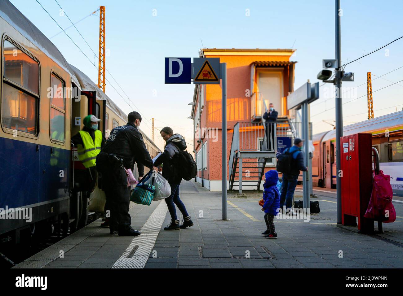 Ein deutscher Grenzpolizist hilft einer ukrainischen Familie, die vor dem Krieg flüchtete, in den Zug zu steigen. Stockfoto