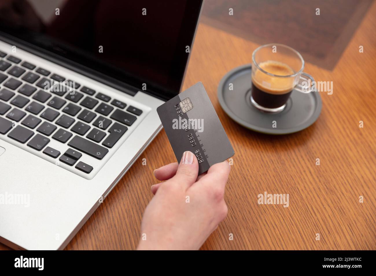 Hände mit Plastikkreditkarte und Laptop, Holztisch Hintergrund, Nahaufnahme. Online-Shopping-Konzept Stockfoto