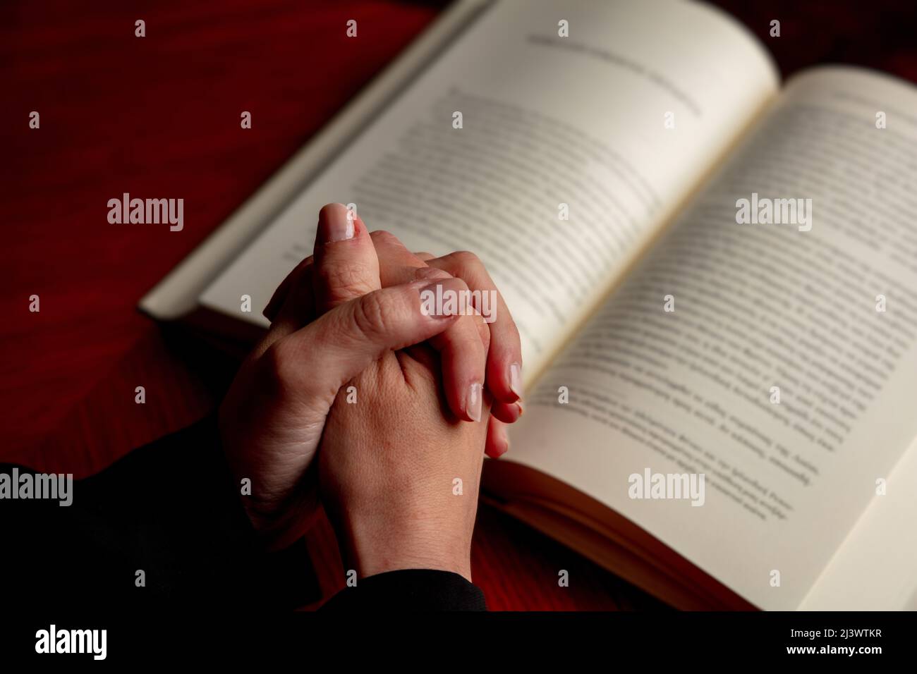 Beten Sie zu Gott, Glauben, Religion und Spiritualität Konzept. Gebet, Frau überreicht ein offenes Buch der Heiligen Bibel, Holzschreibtisch Hintergrund. Stockfoto