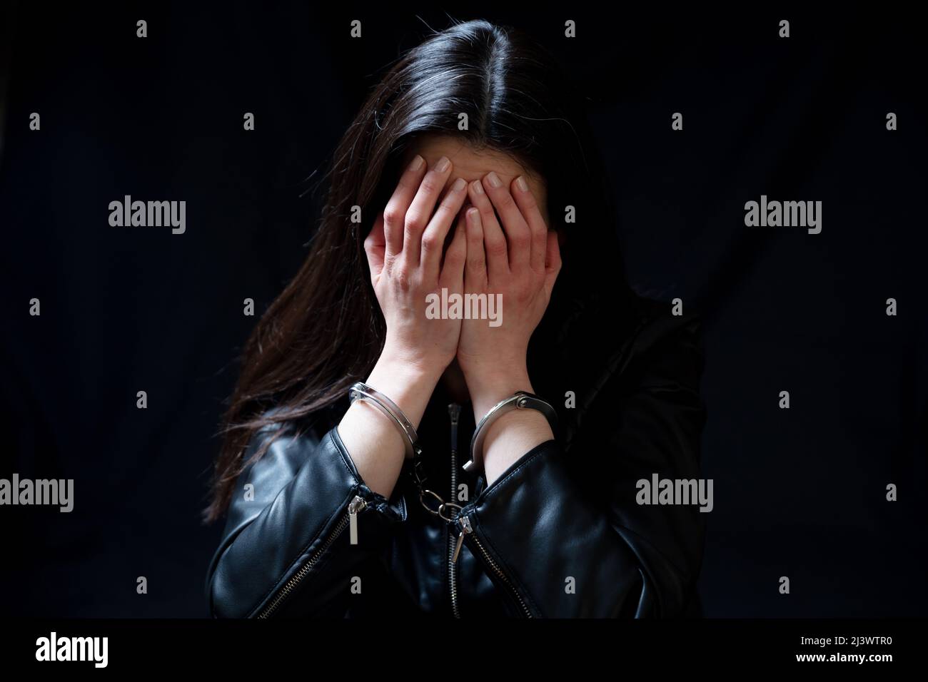 Eine junge Frau bedeckt das Auge, traurig und vernarbt in einem dunklen Raum. Angst und Verzweiflung Konzept Stockfoto
