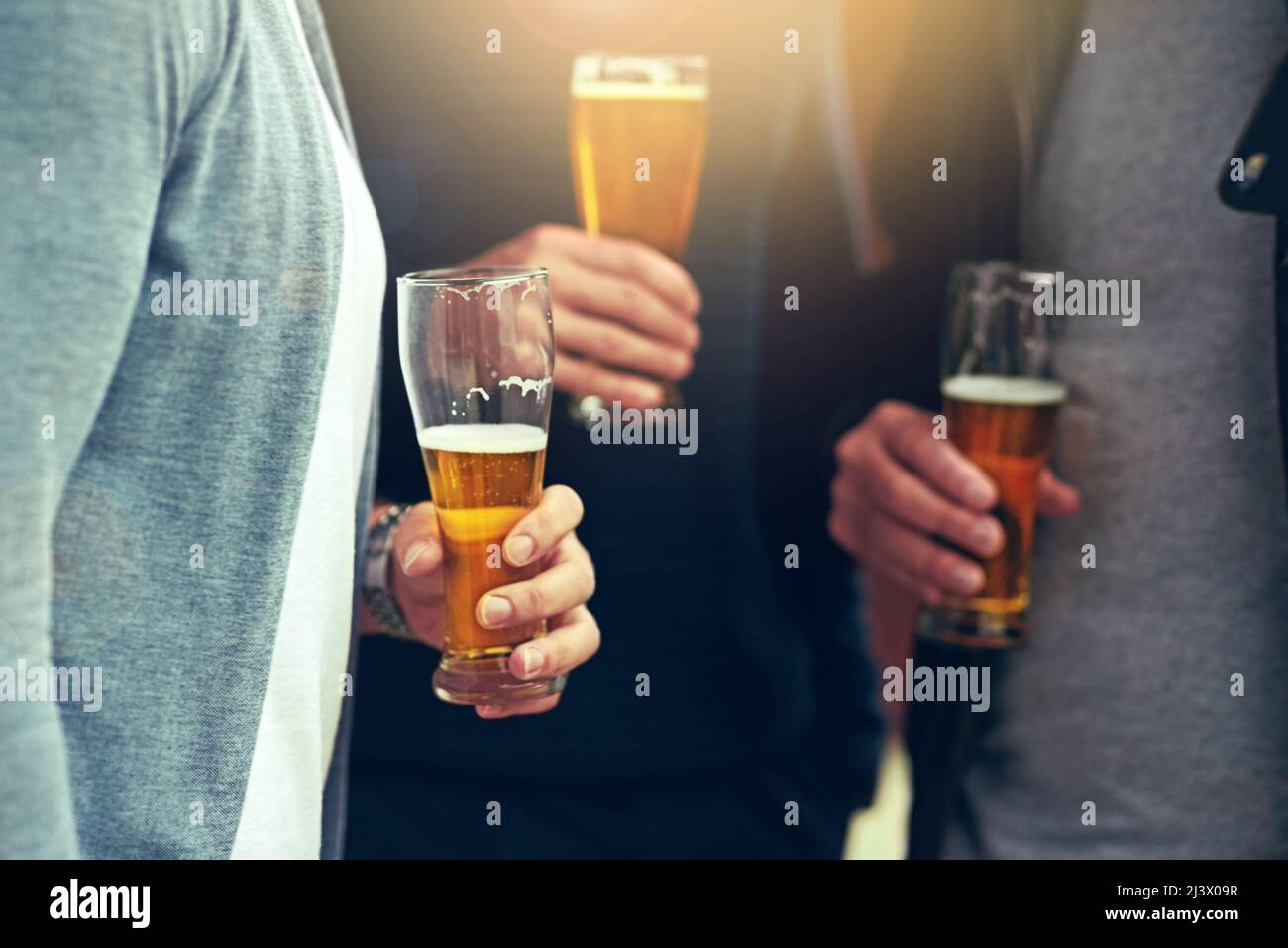 Gute Freunde, gutes Bier. Eine kurze Aufnahme einer Gruppe von nicht identifizierbaren Freunden, die zusammen ein Bier trinken. Stockfoto