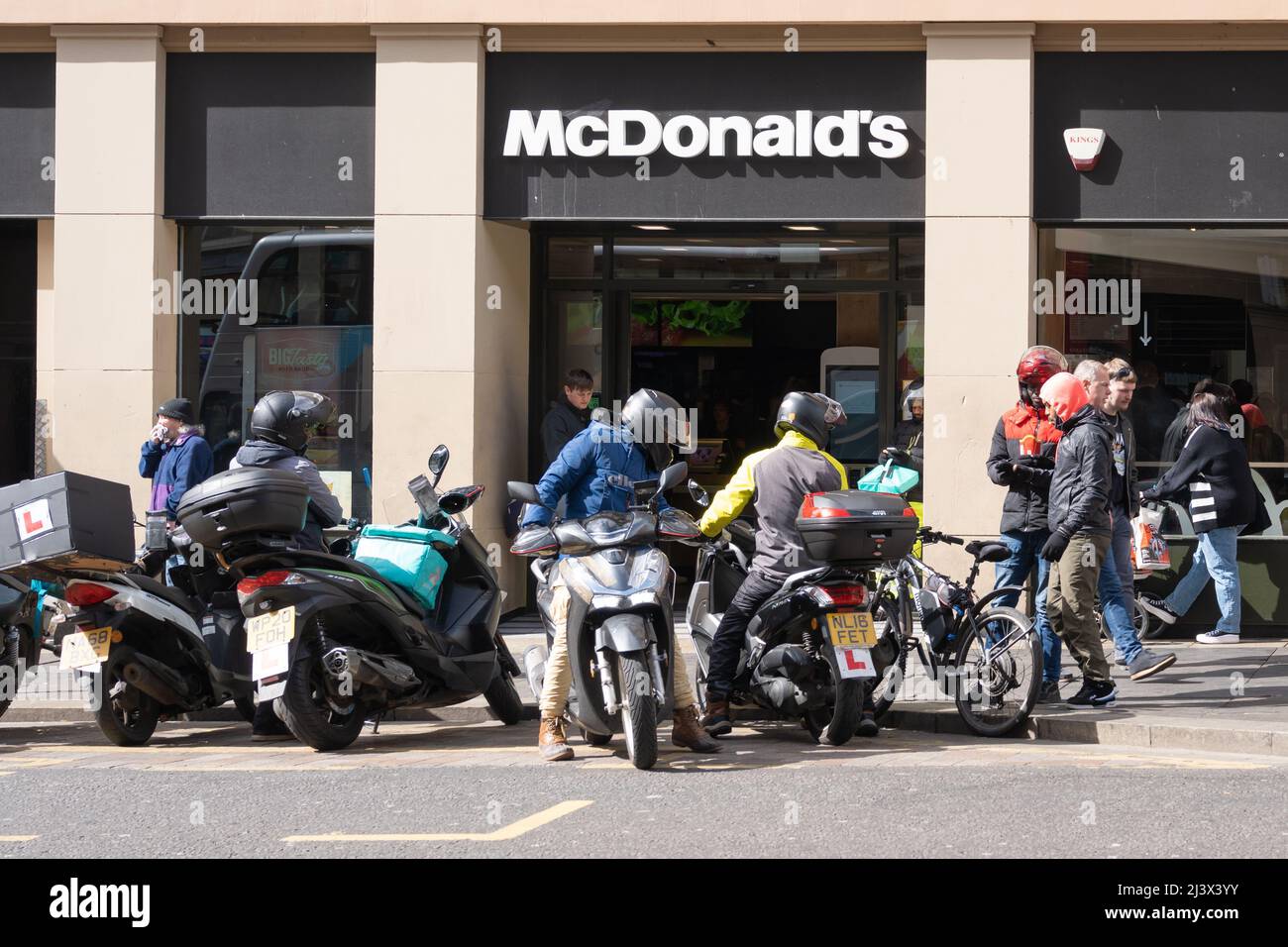 Gig Economy. Vor einer Niederlassung von McDonalds versammeln sich die Kuriere für die Lieferung von Motorrad- und Fahrradkost, die ihre Arbeit in Newcastle upon Tyne, Großbritannien, erwarten. Stockfoto