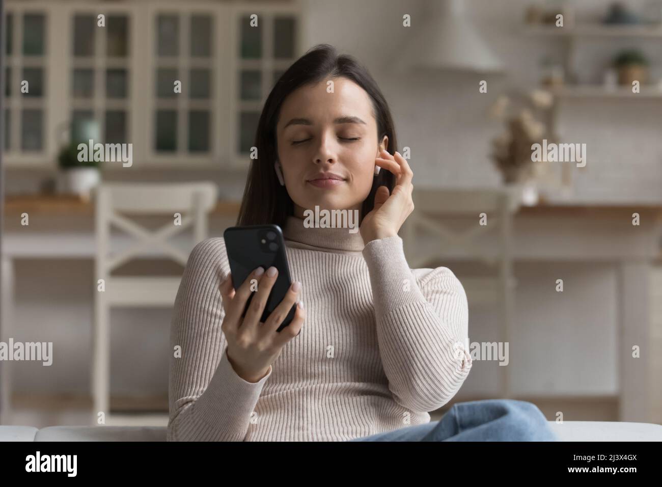 Friedliche Smartphone-Nutzer Mädchen berühren drahtlose Kopfhörer im Ohr Stockfoto