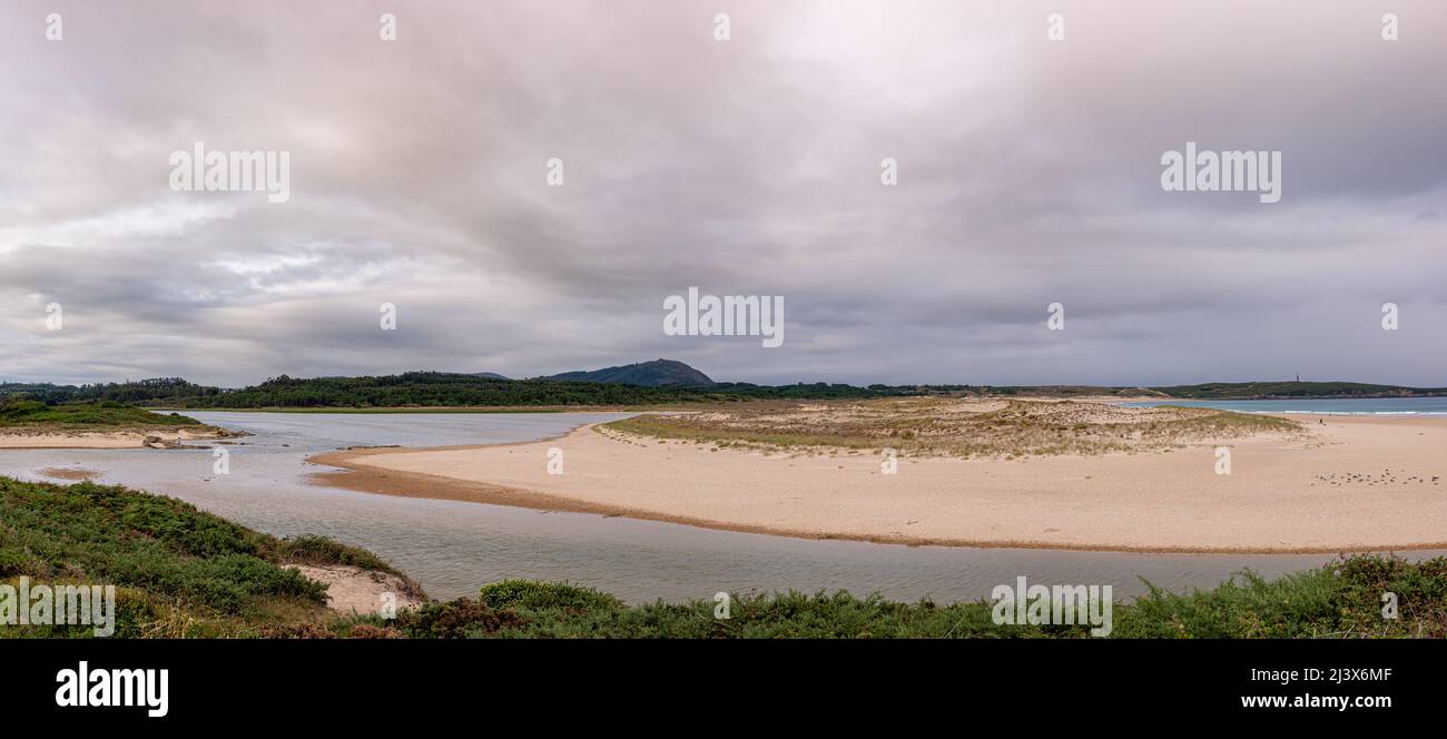 Sandinsel zwischen zwei Gewässern im Meer mit dem Leuchtturm Punta Frouxeira im Hintergrund in Galicien Stockfoto