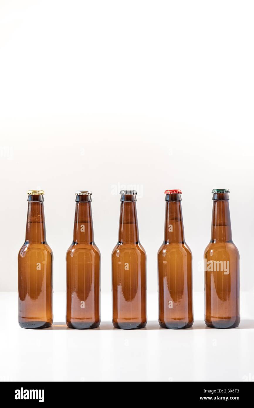 Fünf Flaschen unbeschriftetes Bier mit verschiedenfarbigen Abzeichen Stockfoto
