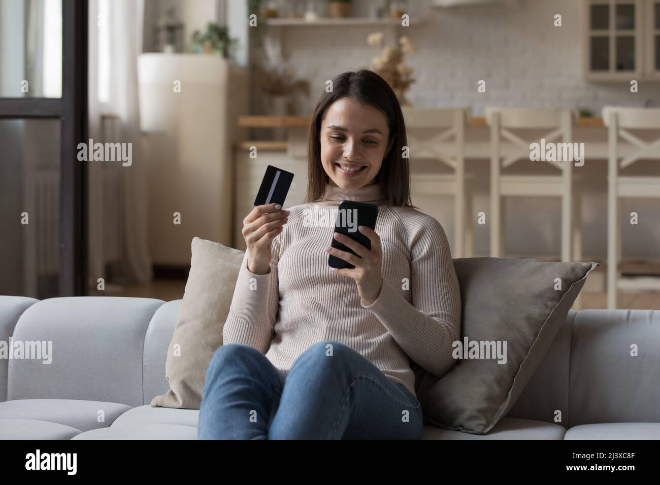 Fröhliche junge Kundin, die Geld von der Kreditkarte ausgibt Stockfoto