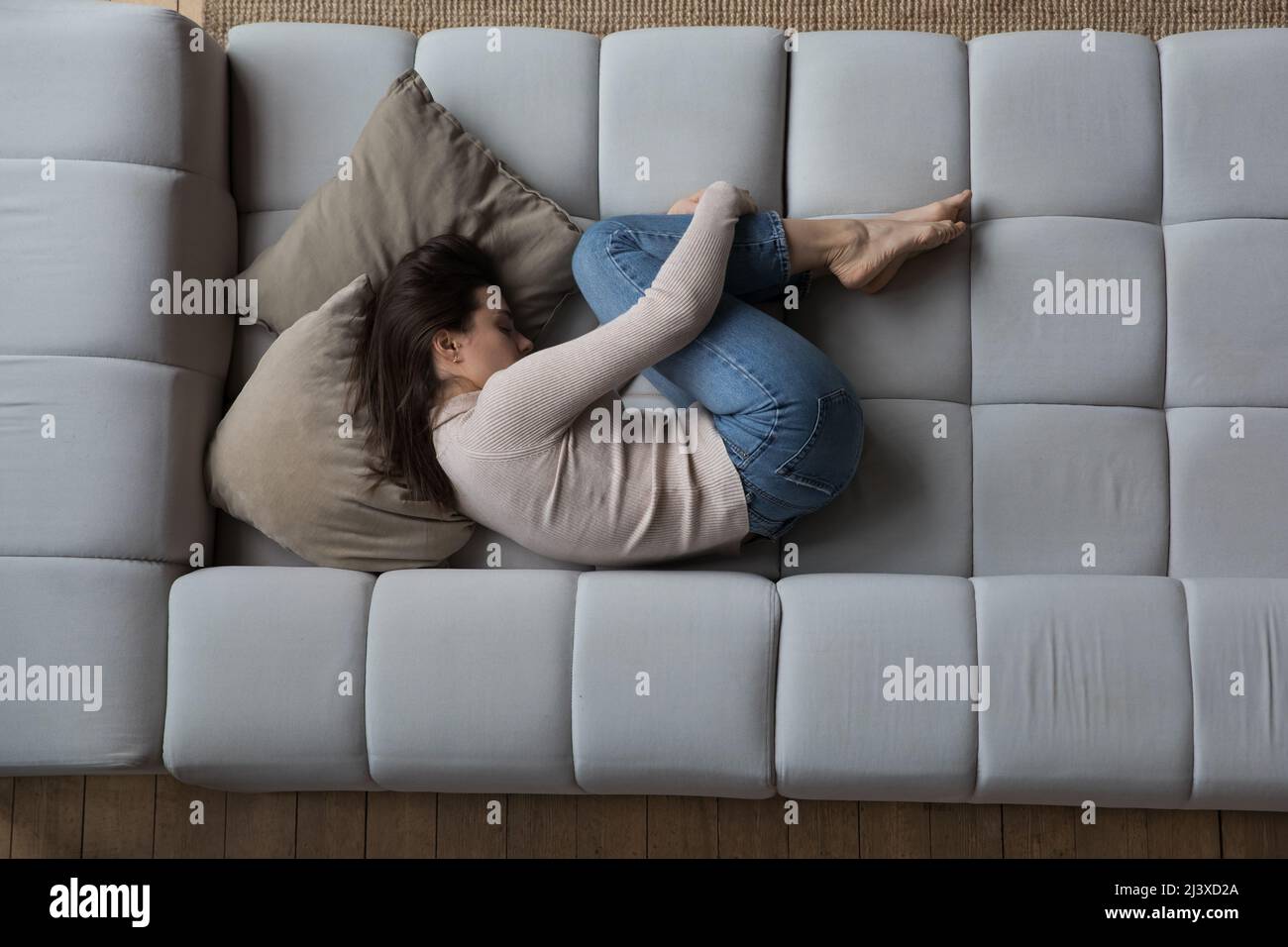 Frustriert deprimiert Millennial Mädchen in Embryo-Pose auf der Couch liegen Stockfoto
